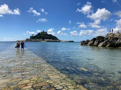 a group of people walking in the water near an island at Foxglove Field Glamping in Perranuthnoe