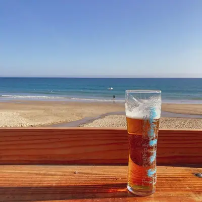 a glass of beer sitting on a table near the beach at Foxglove Field Glamping in Perranuthnoe