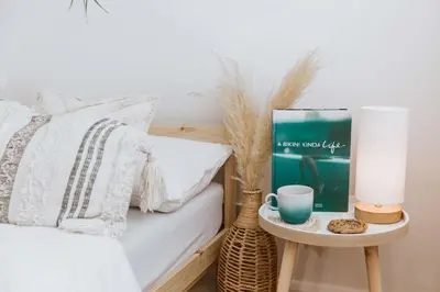 a bed with a table with a book and a cup on it at The Surf House Fistral in Newquay