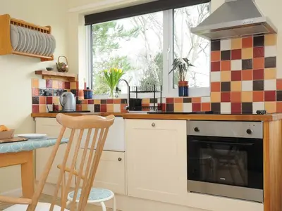 a kitchen with a stove top oven next to a window at Sea Drift in St Austell