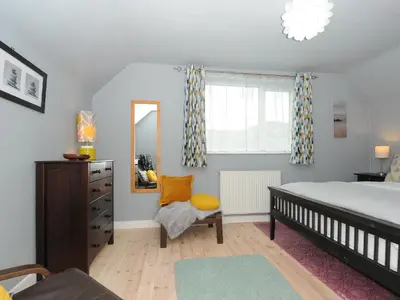 a bedroom with a bed and a mirror and a chair at Sea Drift in St Austell