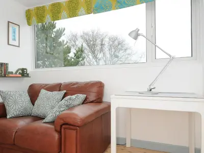 a brown leather chair sitting in front of a window at Sea Drift in St Austell