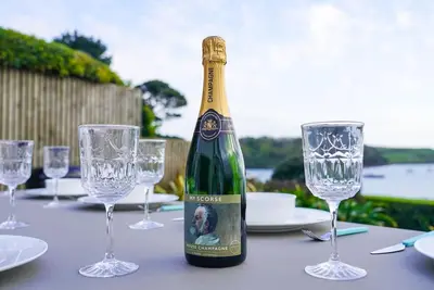 a bottle of champagne sitting on a table with glasses at Beachfront home with spectacular sea views in Saint Mawes