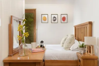 a bedroom with a bed and a table with a mirror at 10 Stonerush Valley in Looe