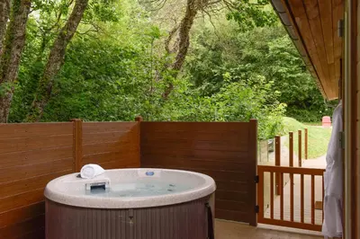 a hot tub on a patio with a wooden fence at 10 Stonerush Valley in Looe