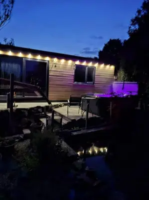 a house with lights on the side of it at night at Cosy Cornish Cabin in St Austell