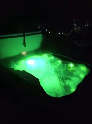 a green pool of water at night with lights at Cosy Cornish Cabin in St Austell