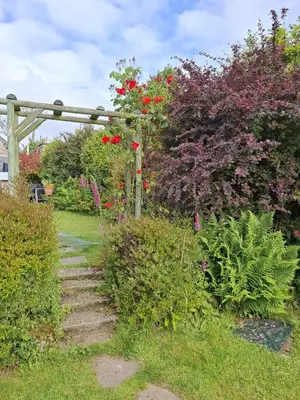 a garden with flowering plants and a wooden fence at Cosy Cornish Cabin in St Austell