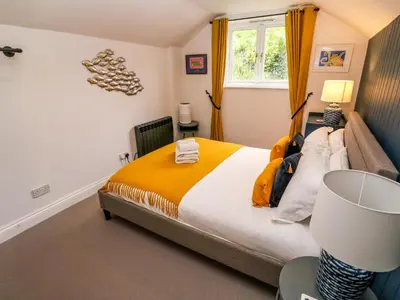 a bedroom with a bed with an orange blanket at Winterbrook Cottage in St Austell