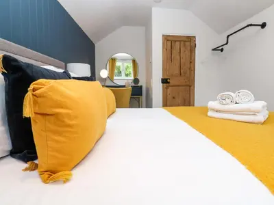 a bedroom with a bed with yellow and black pillows at Winterbrook Cottage in St Austell