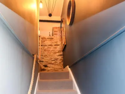 a staircase in a house with a stone wall at Winterbrook Cottage in St Austell