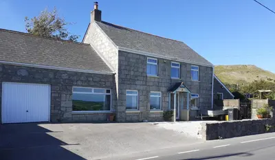 a large stone house with a white garage at Moonraker Room with a View with ensuite shower room in St Austell