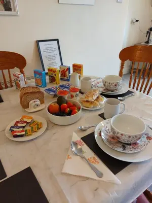 a table with plates and cups and food on it at Moonraker Room with a View with ensuite shower room in St Austell