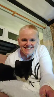 a woman is smiling next to a black and white cat at Moonraker Room with a View with ensuite shower room in St Austell