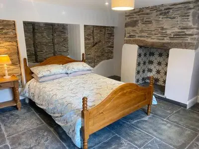 a bedroom with a wooden bed in a room at Tregue Cottage in Camelford