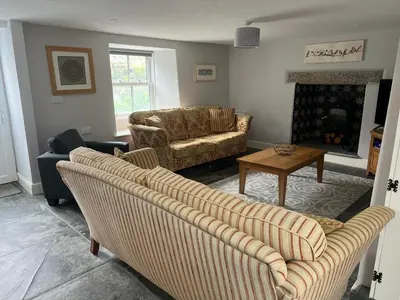 a living room with two couches and a table at Tregue Cottage in Camelford