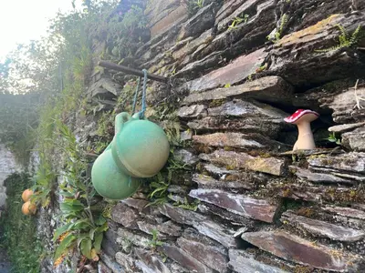 a green pot hanging on a stone wall at Tregue Cottage in Camelford