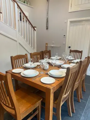 a wooden table with chairs and plates and wine glasses at Tregue Cottage in Camelford