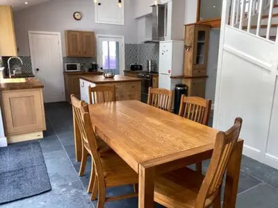 a kitchen with a wooden table and wooden chairs at Tregue Cottage in Camelford