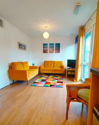 a living room with two yellow couches and a colorful rug at Kerenza Cottage - Families & Pets in Uny Lelant