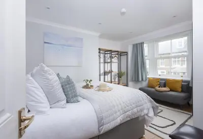 a bedroom with a large white bed and a couch at 7 Wheal Ayr, St Ives in St Ives