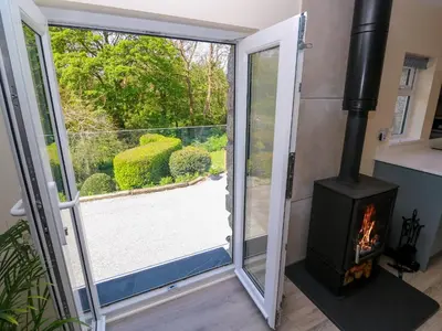 a fireplace in a tiny house with a sliding glass door at Chy-An-Oula in Falmouth