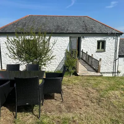 a table and chairs in front of a white building at The Hay Loft in Porkellis