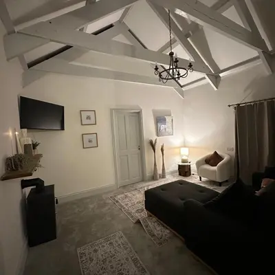 a living room with a couch and a chandelier at The Hay Loft in Porkellis