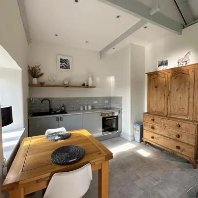 a kitchen with a wooden table and some chairs at The Hay Loft in Porkellis