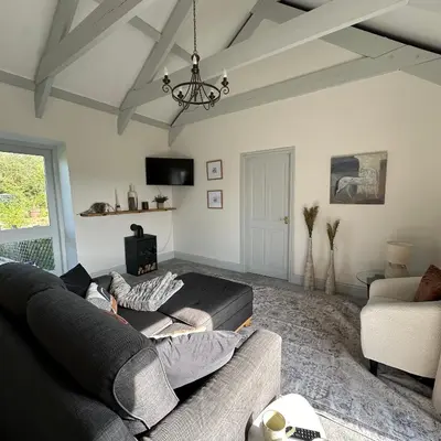 a living room with a couch and a chandelier at The Hay Loft in Porkellis