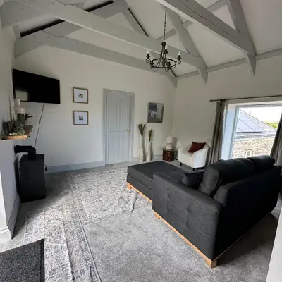 a living room with a black couch and a window at The Hay Loft in Porkellis
