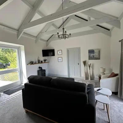 a living room with a black couch and a window at The Hay Loft in Porkellis