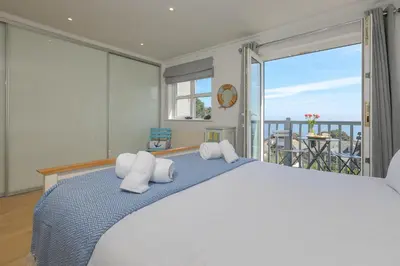 a bedroom with a large bed and a balcony at Chy an Pol in St Ives