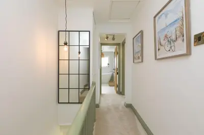 a hallway of a home with white walls and a mirror at Dowran in Hayle
