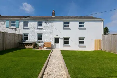 a white house with a green lawn in front of it at Dowran in Hayle