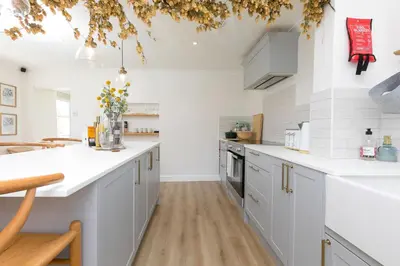 a kitchen with white cabinets and white appliances at Dowran in Hayle