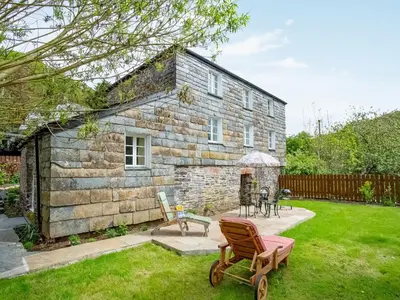 a stone house with a lawn in front of it at Hingham Mill Cottage in Wadebridge