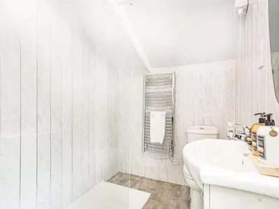 a white bathroom with a sink and a toilet at Hingham Mill Cottage in Wadebridge