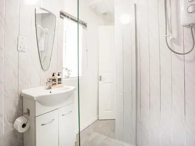 a white bathroom with a sink and a shower at Hingham Mill Cottage in Wadebridge