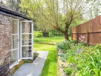 a garden with a window and a brick house at Hingham Mill Cottage in Wadebridge