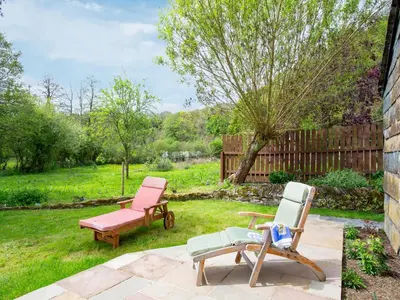 a yard with two chairs and a bench at Hingham Mill Cottage in Wadebridge