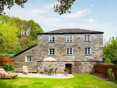an old stone house with a patio in the yard at Hingham Mill Cottage in Wadebridge
