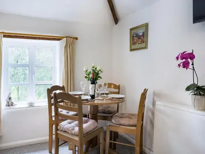 a dining room with a table and chairs and a window at Hingham Mill Cottage in Wadebridge