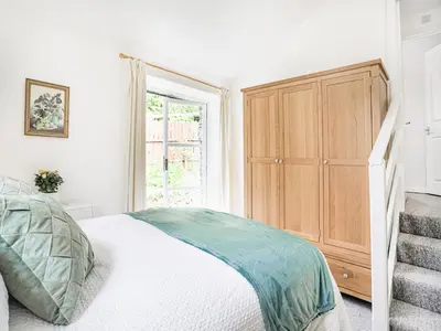a bedroom with a bed and a wooden cabinet at Hingham Mill Cottage in Wadebridge