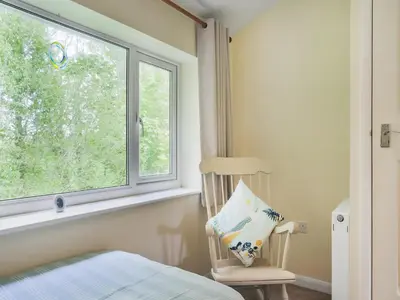 a bedroom with a bed and a chair and a window at Manor Haven - Atlantic Reach in Saint Columb Major