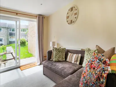 a living room with a couch and a clock on the wall at Manor Haven - Atlantic Reach in Saint Columb Major