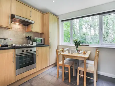 a kitchen with wooden cabinets and a table with chairs at Manor Haven - Atlantic Reach in Saint Columb Major