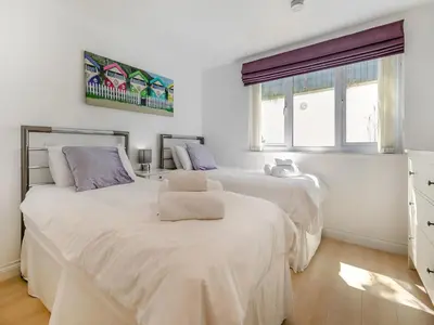 two beds in a white room with two windows at Chapel View in Carbis Bay