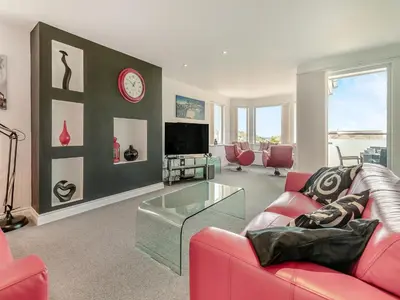 a living room with a red couch and a tv at Chapel View in Carbis Bay
