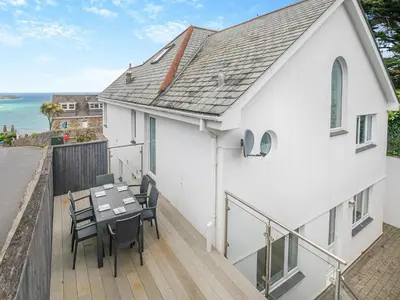 a house with a balcony with a table and chairs at Chapel View in Carbis Bay